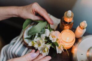 woman holding flowers with essential oils and candle lit nearby