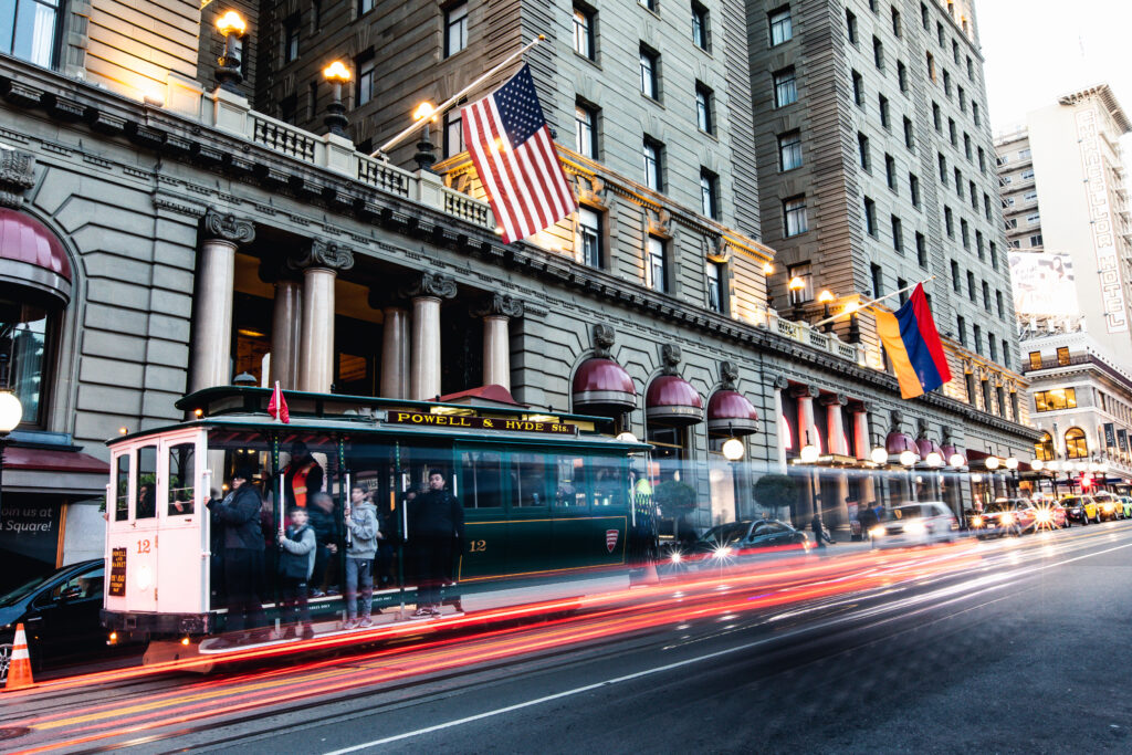A cable car in San Francisco whizzes down Powell Street in front of the Westin St. Francis Hotel at dusk